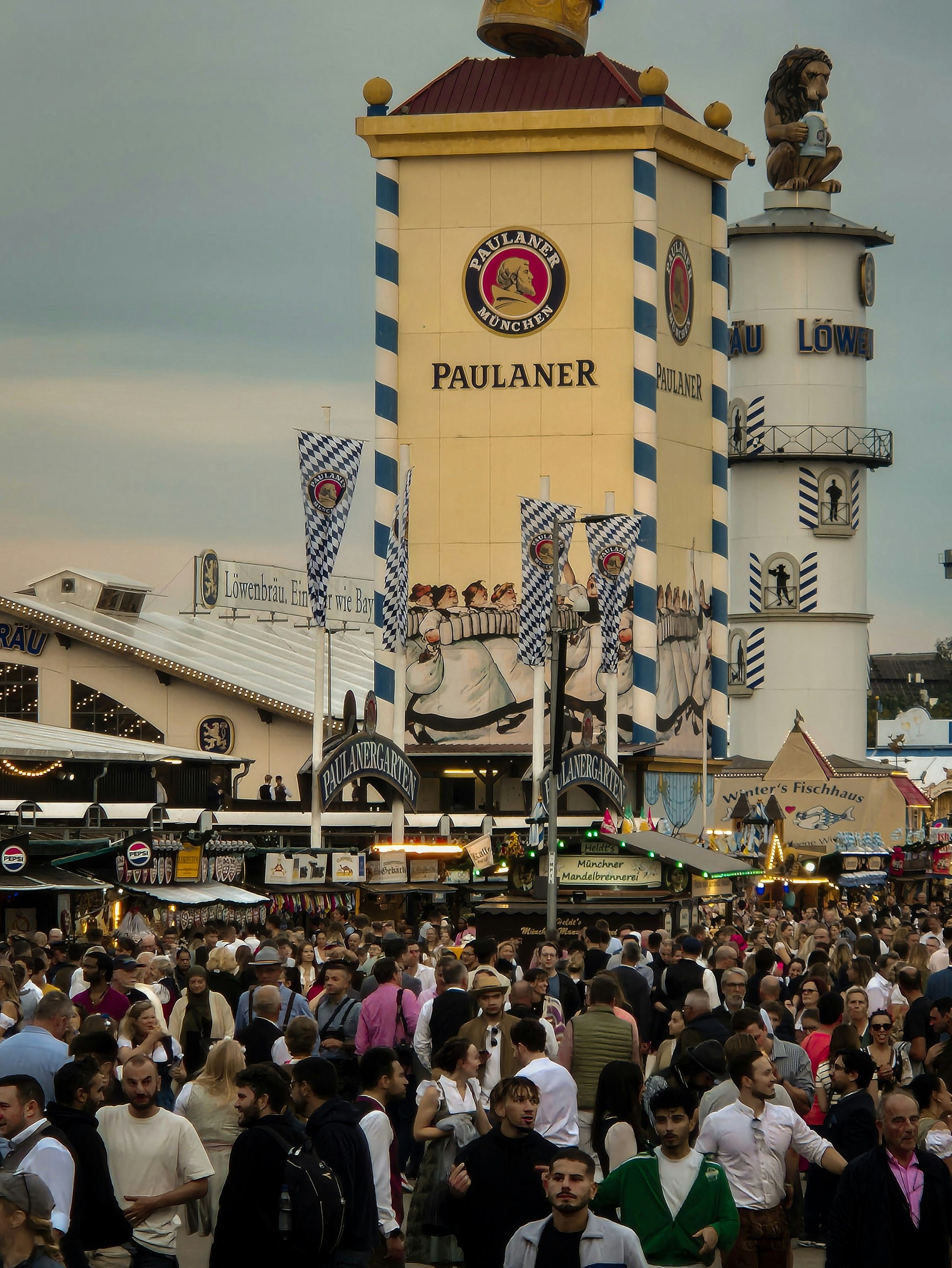 A torre da tenda Paulaner e a torre do Löwenbräu sobre a multidão na alameda central da Theresienwiese